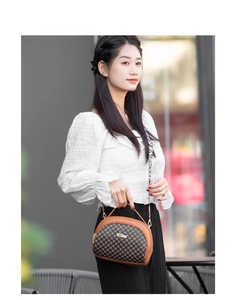 Detail of checkered shell bag with brown faux leather trim and wide lettered strap