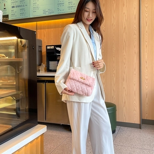 Pink faux fur quilted crossbody bag with gold chain strap shown on a model in a cafe