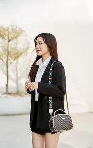 Close-up of shell-shaped handbag with vintage print and LOVE letter wide strap