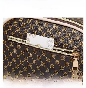 Detail of brown embossed leather shell bag showing gold pattern and back zipper pocket