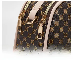 Close-up of smooth gold dual zippers and printed leather texture on a shell handbag
