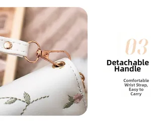 Detail einer weißen Lederbörse mit Blumenstickerei und abnehmbarer Handschlaufe