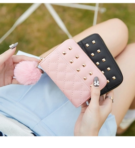 Close-up of stylish studded small purses with quilted pattern and fluffy ball pendants