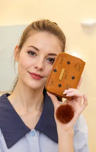 Close-up of brown patterned small wallet with zipper closure and fluffy pompom keychain