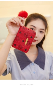 Detail of red pebbled leather mini wallet with gold zipper and fluffy faux fur pompom