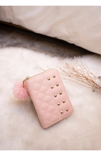 Close-up of pink quilted purse with golden studs and a soft pom-pom zipper charm