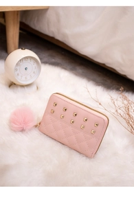 Close-up of pink faux leather purse with quilted pattern, gold studs and pom-pom charm