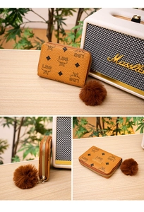 Close-up of yellow faux leather wallet with black printed patterns and brown fur pom-pom