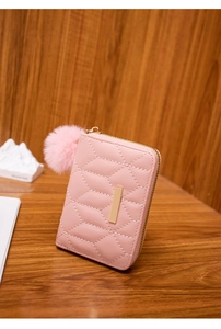 Dettaglio portafoglio in pelle sintetica rosa trapuntata con pompon e cerniera dorata