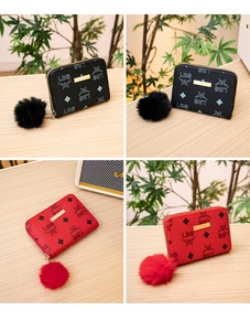 Close-up of small card wallets with litchi grain texture and fluffy pompom keychain detail