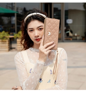 Detail of nude pink quilted long wallet with white butterfly buckle and plush ball charm