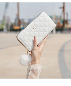 Detail of white quilted PU leather long wallet with butterfly logo and fur pompom