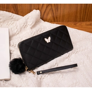Detail of black quilted leather long wallet with butterfly clasp and fur pompom