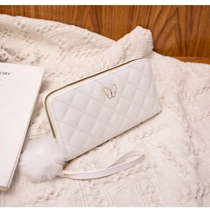 Close-up of white quilted long wallet with golden butterfly ornament and plush pompom