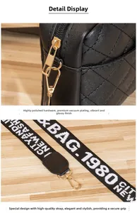 Détail du sac noir matelassé avec garnitures dorées et bandoulière large tissée