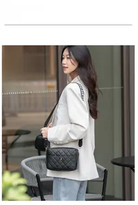 Détail d'un sac bandoulière matelassé avec large sangle logo et petit porte-monnaie rond