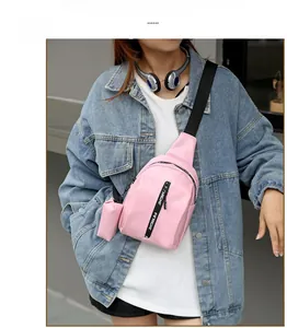 Rosafarbene Mini-Umhängetasche mit Logo-Gurt, getragen von einem Modell in urbaner Umgebung