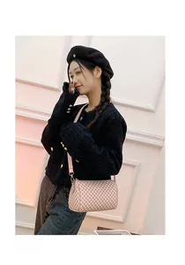 Pink cylinder crossbody bag with geometric checkered pattern and wide shoulder strap