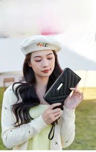 Outdoor model display of black quilted long wallet with golden metal plaque and wristlet