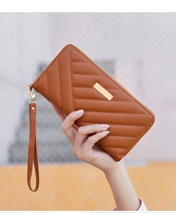 Detail of caramel brown quilted long wallet featuring gold hardware and a wrist strap