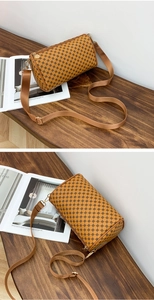 Brown floral cylinder crossbody bag with wide strap on a wooden bench setting