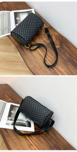 Macro view of black barrel bag featuring grey geometric patterns and gold metal hooks