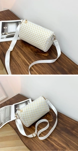 Detail of white cylinder bag with yellow floral print and nylon shoulder strap
