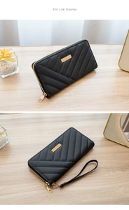 Close-up of black quilted leather long wallet with gold zipper and wristlet strap