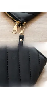 Detail of black quilted long wallet with V-stitch pattern and gold metal hardware