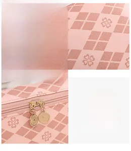 Detail of pink lychee leather vanity bag with clover print and gold metal zippers