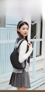 Fashionable black nylon half-moon crossbody bag shown on a model in an outdoor setting