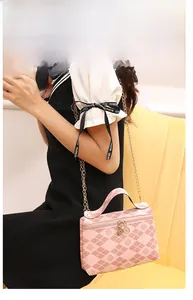 Detail of pink diamond pattern quilted handbag with clover print and gold chain strap