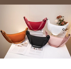 Flat lay of five nylon dumpling crossbody bags in orange, red, white, black and pink colors