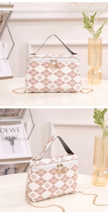 Detailed view of dual-zipper closure and chain strap on quilted clover pattern bag