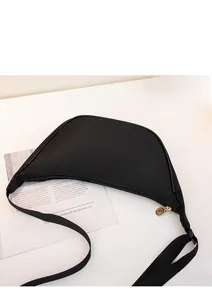 Close-up of a black nylon crescent bag with gold zippers and adjustable shoulder strap