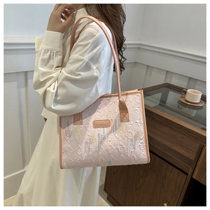 Detailed close-up of pink tote bag featuring quilted pattern and embroidery on elegant model
