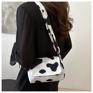 Detail of crossbody bag featuring black and white cow print with adjustable strap