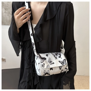 Detailed close-up of a white butterfly print crossbody bag worn with a black shirt