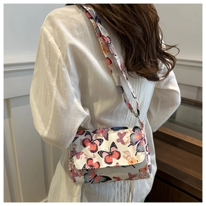 Close-up of white crossbody bag with butterfly prints and matching wide shoulder strap