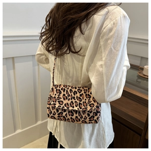 Detailed view of leopard print crossbody bag worn by a model in a cozy indoor setting