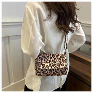 Detail view of a leopard print crossbody bag with satin finish worn by a model