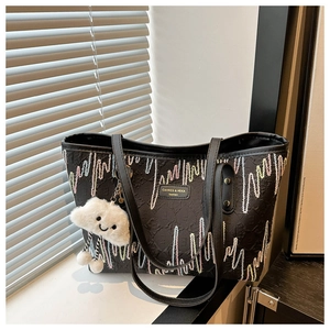 Detalle de bolso tote negro con bordado ondulado colorido y colgante de nube blanca