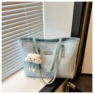 Detalle de bolso tote de jacquard azul claro con corazones bordados y colgante nube