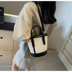 Detail view of retro contrast bucket bag with canvas texture and leather straps on model