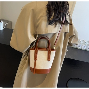 Detail of a vintage canvas and brown leather bucket bag shown on model for size and fit