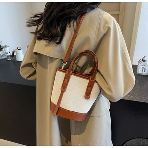 Detailed view of bicolor canvas bucket bag featuring premium brown leather trim and strap