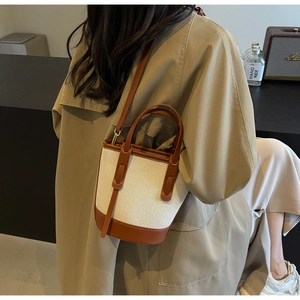 Detail of color-block bucket bag in off-white canvas and brown leather on model