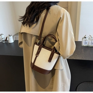 Detail of vintage canvas and brown leather bucket bag shown on model for lifestyle view