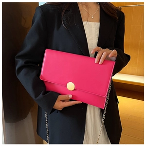 Dettaglio della pochette rosa a busta con fibbia circolare oro opaco e catenella