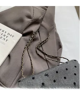 Detail of grey herringbone fabric handbag with black polka dots and gold chain strap